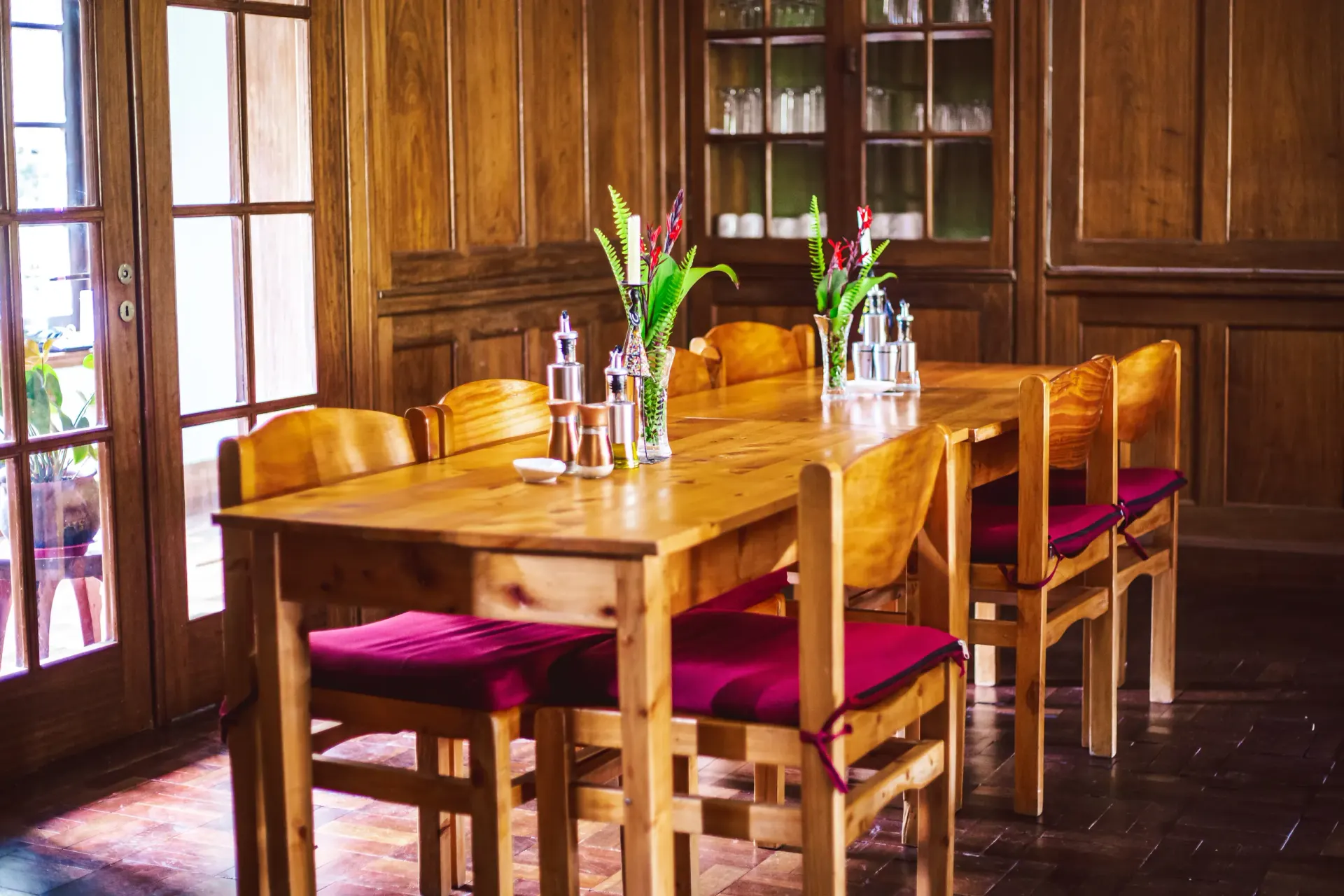 The Mullers dining room set for a meal, warmed by lamplight and seasonal flowers
