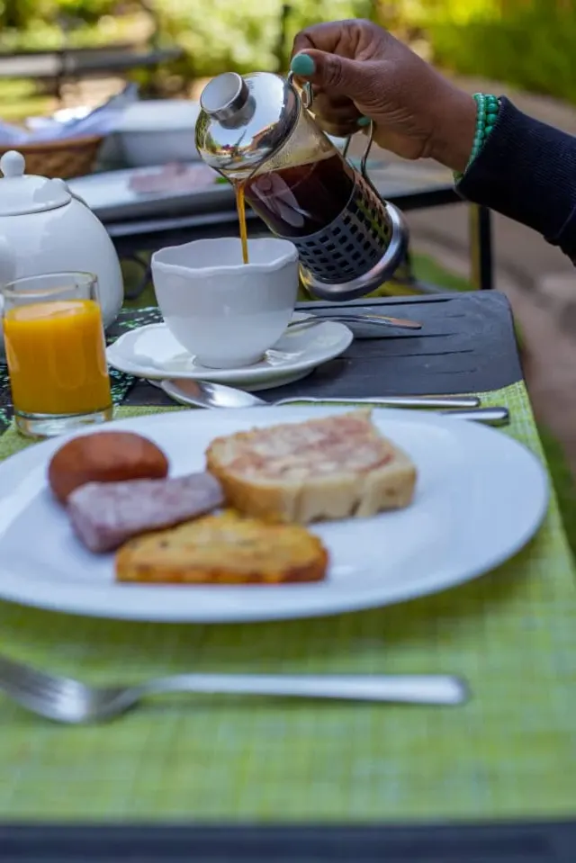 Coffee poured from a French press over a breakfast plate in the garden light at Mullers